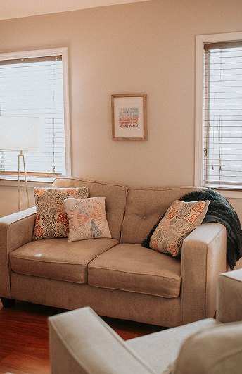 A sofa and armchair in the Willow Tree office, framed art and a bright window behind them.