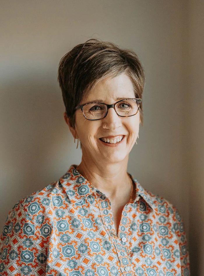 Kelly Wood, LCSW, smiling, wearing glasses and a patterned blouse.
